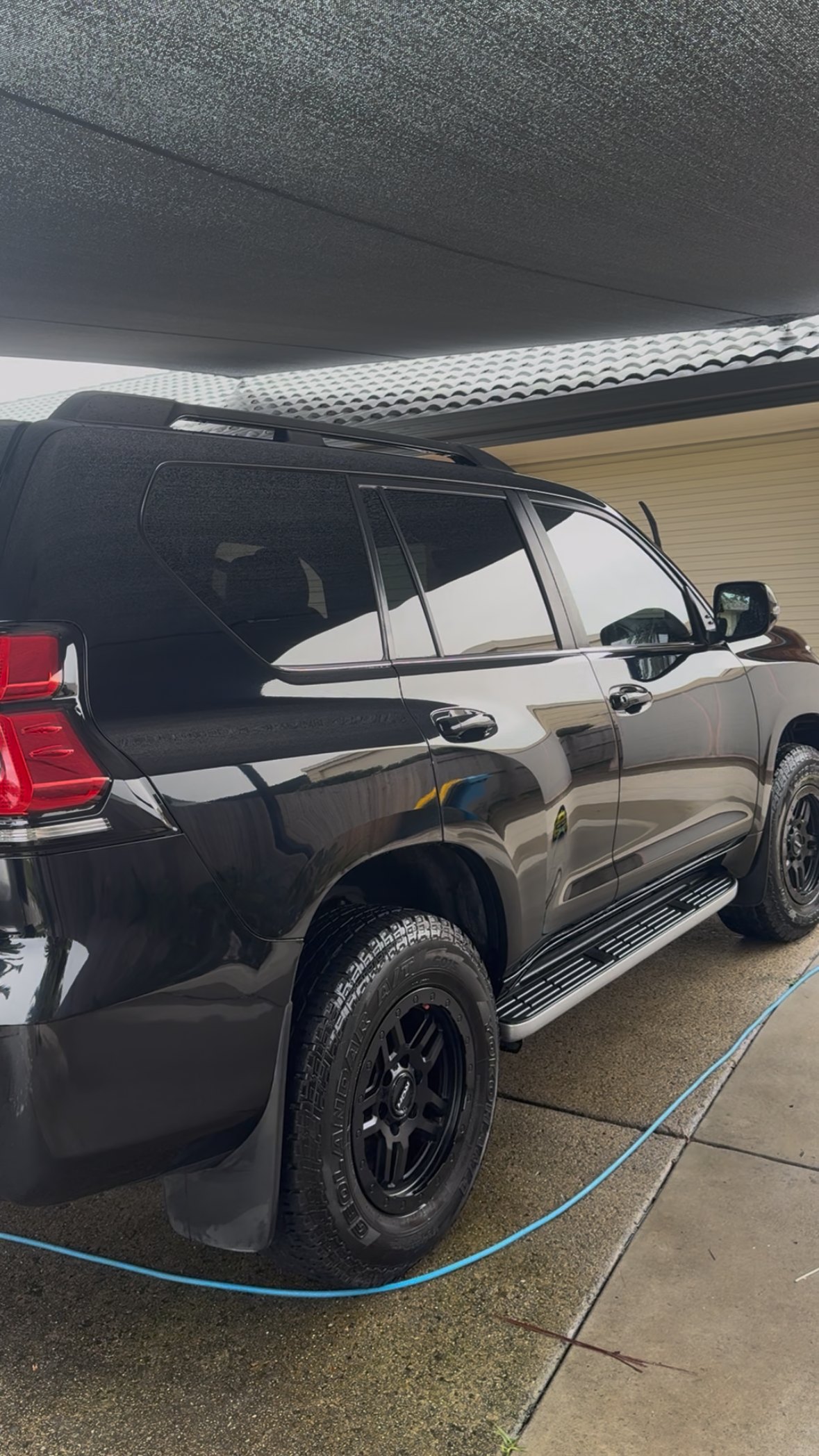 Black Toyota Prado detailed to a deep gloss under a carport