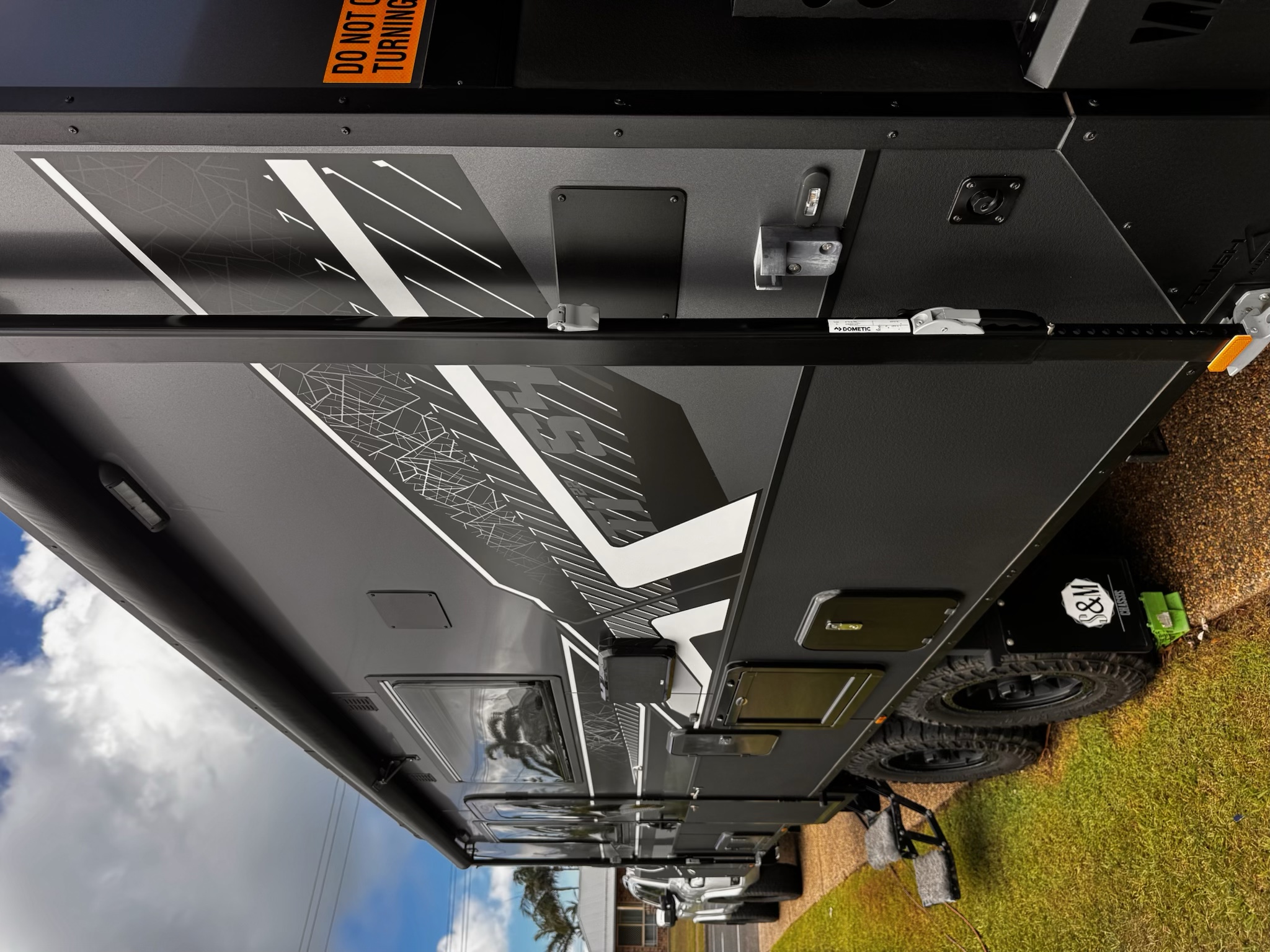 Detailed side panel and wheels of a black off-road caravan