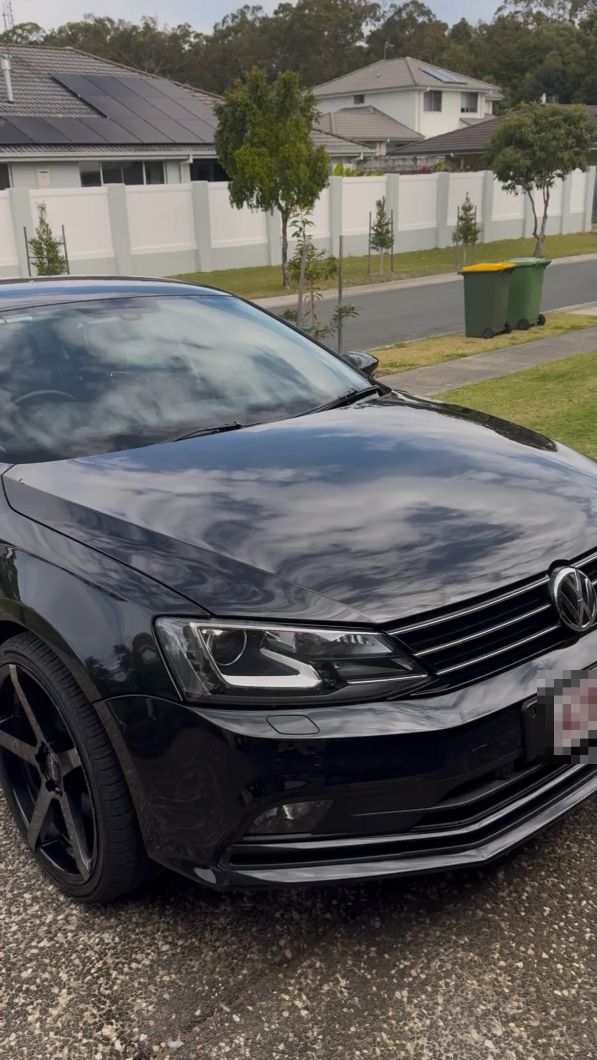 Finished ceramic coated black sedan with deep gloss and mirror reflections, whole car in frame