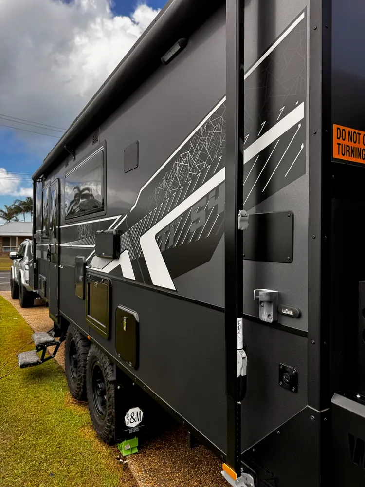 Detailed side panel and wheels of a black off-road caravan